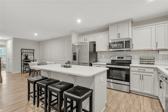 5845 Austin Woods Dr, North Chesterfield, VA 23234 - kitchen featuring appliances with stainless steel finishes, a kitchen island, a kitchen breakfast bar, light wood-style floors, and light countertops