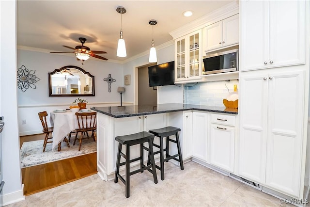 5618 Buxton Ct, Chester, VA 23831 - kitchen with stainless steel microwave, a peninsula, crown molding, glass insert cabinets, and pendant lighting