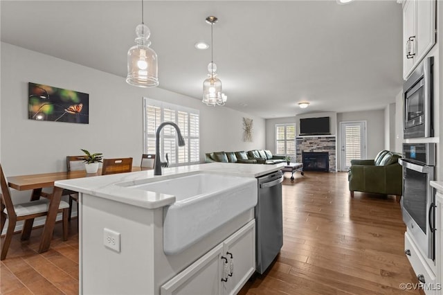 3391 Rock Creek Villa Dr, Quinton, VA 23141 - kitchen featuring appliances with stainless steel finishes, a fireplace, pendant lighting, dark wood-style floors, and white cabinetry