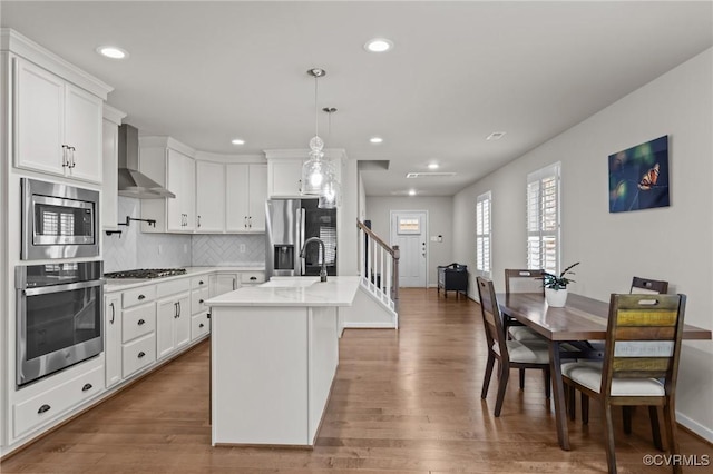 3391 Rock Creek Villa Dr, Quinton, VA 23141 - kitchen with stainless steel appliances, wall chimney exhaust hood, recessed lighting, white cabinetry, and wood finished floors