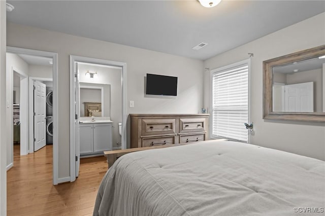 3391 Rock Creek Villa Dr, Quinton, VA 23141 - bedroom featuring stacked washing machine and dryer, light wood-type flooring, and connected bathroom