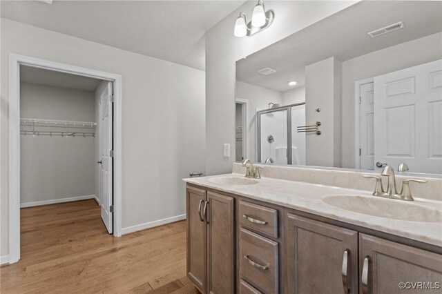 3391 Rock Creek Villa Dr, Quinton, VA 23141 - bathroom featuring a shower stall, double vanity, wood finished floors, and a spacious closet