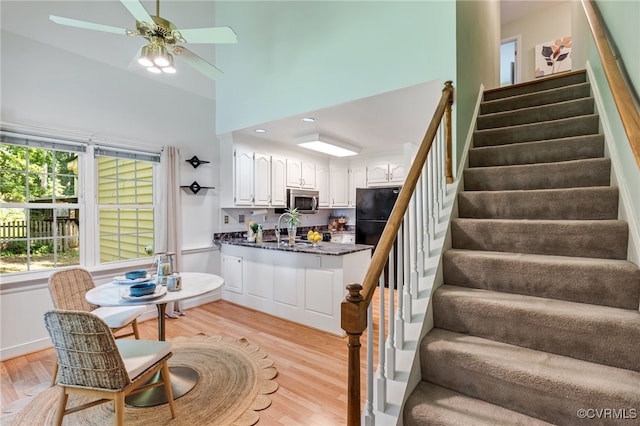 1424 Laurel Top Dr, Midlothian, VA 23114 - kitchen featuring a peninsula, stainless steel microwave, white cabinetry, light wood-style flooring, and a towering ceiling