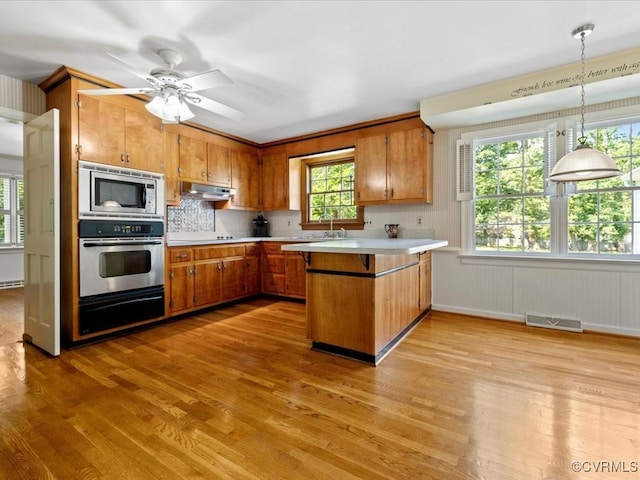 2340 Scarsborough Dr, North Chesterfield, VA 23235 - kitchen with stainless steel appliances, a warming drawer, a peninsula, brown cabinetry, and light wood finished floors