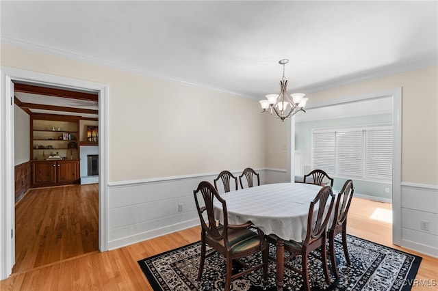 2730 Dalkeith Dr, Henrico, VA 23233 - dining area featuring a chandelier, light wood-type flooring, a wainscoted wall, crown molding, and a fireplace