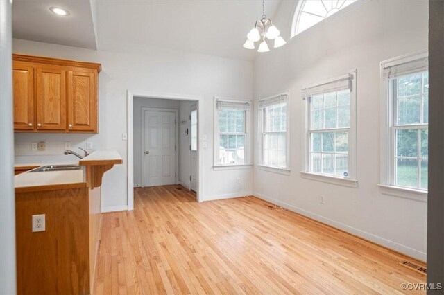 17220 Dawn Ct, Amelia Courthouse, VA 23002 - kitchen featuring light countertops, a chandelier, light wood-style floors, brown cabinets, and pendant lighting