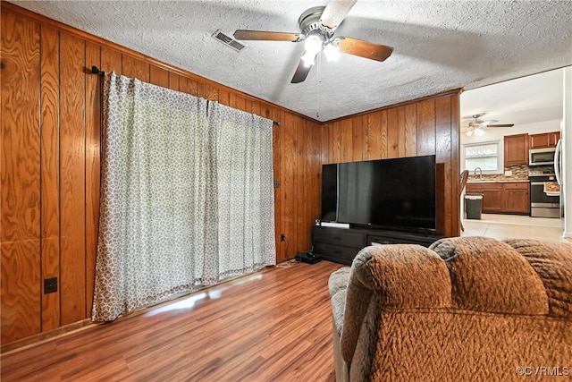 1593 Baxter Rd, Prince George, VA 23875 - living room with ceiling fan, light wood-style flooring, a textured ceiling, and wood walls