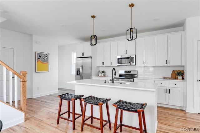 18 W 29th St, Richmond, VA 23223 - kitchen featuring stainless steel appliances, a kitchen bar, light wood-style floors, an island with sink, and light countertops