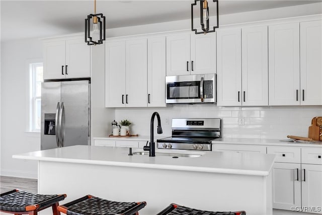 18 W 29th St, Richmond, VA 23223 - kitchen with stainless steel appliances, a center island with sink, light countertops, white cabinetry, and tasteful backsplash