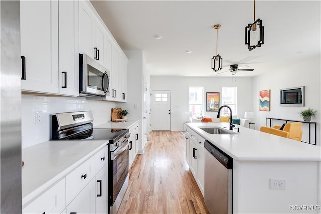 18 W 29th St, Richmond, VA 23223 - kitchen featuring appliances with stainless steel finishes, a ceiling fan, light wood-style flooring, a center island with sink, and light countertops