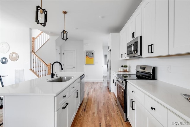 18 W 29th St, Richmond, VA 23223 - kitchen with appliances with stainless steel finishes, light wood-style flooring, a center island with sink, light countertops, and white cabinets