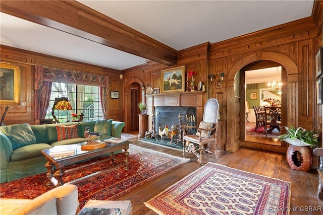 985 Kingston Ln, North, VA 23128 - living area with arched walkways, wooden walls, wood-type flooring, beam ceiling, and a warm lit fireplace