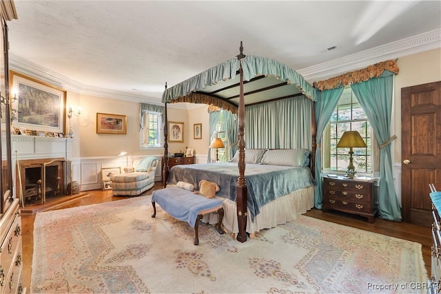 985 Kingston Ln, North, VA 23128 - bedroom with crown molding, multiple windows, a wainscoted wall, wood finished floors, and a fireplace with raised hearth