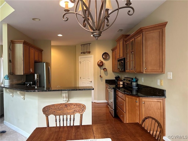 5623 Virginia Park Dr, Providence Forge, VA 23140 - kitchen featuring appliances with stainless steel finishes, brown cabinets, a chandelier, a peninsula, and dark stone counters
