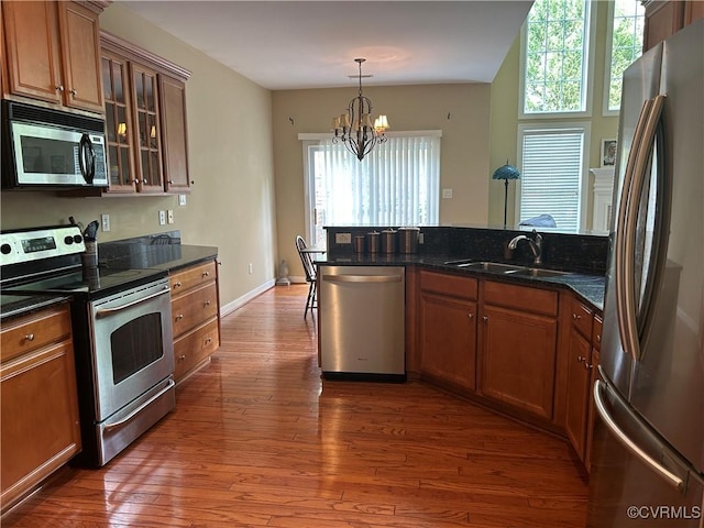 5623 Virginia Park Dr, Providence Forge, VA 23140 - kitchen featuring stainless steel appliances, a chandelier, brown cabinetry, wood-type flooring, and glass insert cabinets