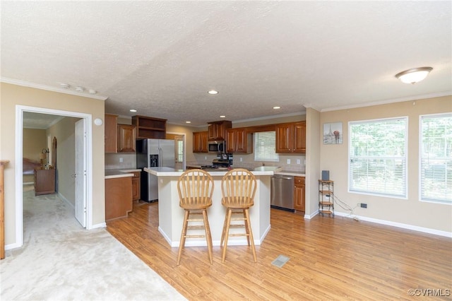 3737 Shelton Store Rd, Buckingham, VA 23921 - kitchen with appliances with stainless steel finishes, light countertops, a breakfast bar, a kitchen island, and brown cabinetry