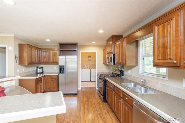 3737 Shelton Store Rd, Buckingham, VA 23921 - kitchen featuring appliances with stainless steel finishes, separate washer and dryer, brown cabinets, crown molding, and light wood-style flooring