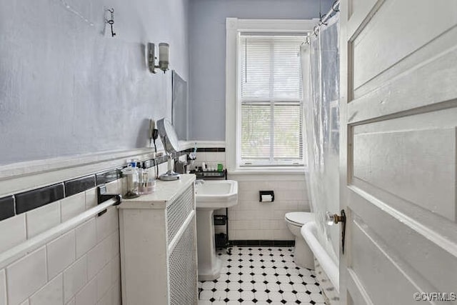 2024 Park Ave, Richmond, VA 23220 - bathroom with tile walls, wainscoting, and shower / bath combination with curtain