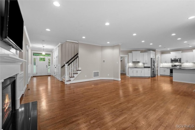 11499 Jack Ln, Hanover, VA 23146 - unfurnished living room with crown molding, a glass covered fireplace, recessed lighting, wood finished floors, and stairway