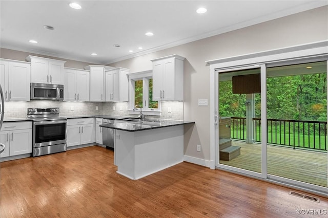 11499 Jack Ln, Hanover, VA 23146 - kitchen featuring appliances with stainless steel finishes, a peninsula, healthy amount of natural light, white cabinets, and crown molding