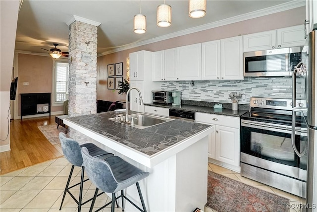 1410 W Clay St, Richmond, VA 23220 - kitchen featuring appliances with stainless steel finishes, ornate columns, dark countertops, ornamental molding, and light tile patterned flooring