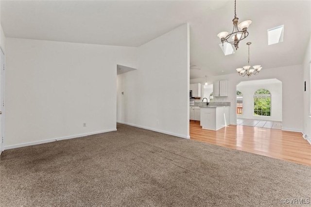 7470 Old Grove Gln, Mechanicsville, VA 23111 - unfurnished living room with light colored carpet, a chandelier, high vaulted ceiling, and arched walkways