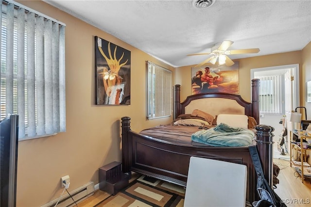 1007 Bolton Rd, Richmond, VA 23225 - bedroom featuring wood finished floors, baseboard heating, a ceiling fan, and a textured ceiling