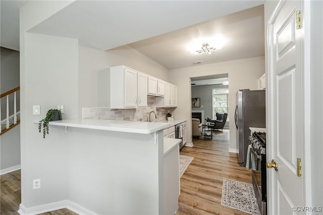 11405 Friars Walk Ct, Glen Allen, VA 23059 - kitchen featuring stove, light wood-style flooring, white cabinets, a kitchen breakfast bar, and light countertops