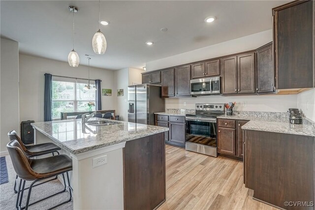 6989 Sir Galahad Rd, Henrico, VA 23231 - kitchen with appliances with stainless steel finishes, light wood-style floors, dark brown cabinetry, a breakfast bar, and an island with sink