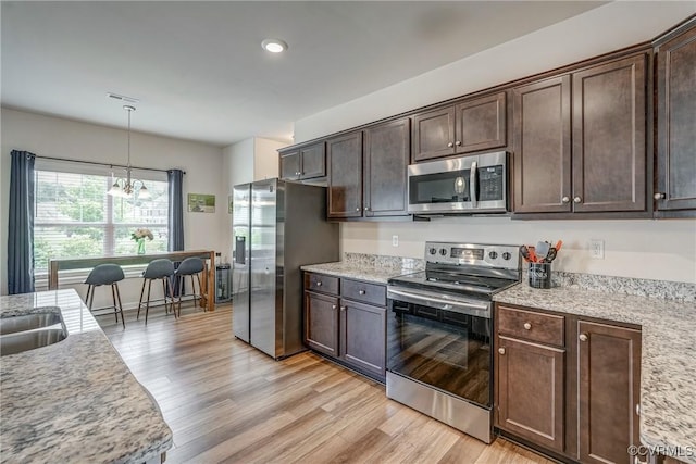 6989 Sir Galahad Rd, Henrico, VA 23231 - kitchen with appliances with stainless steel finishes, dark brown cabinetry, light wood-type flooring, a chandelier, and hanging light fixtures