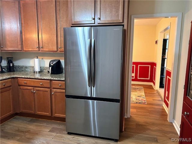 2205 Cox Rd, Henrico, VA 23233 - kitchen with freestanding refrigerator, wood finished floors, wainscoting, light stone countertops, and brown cabinets