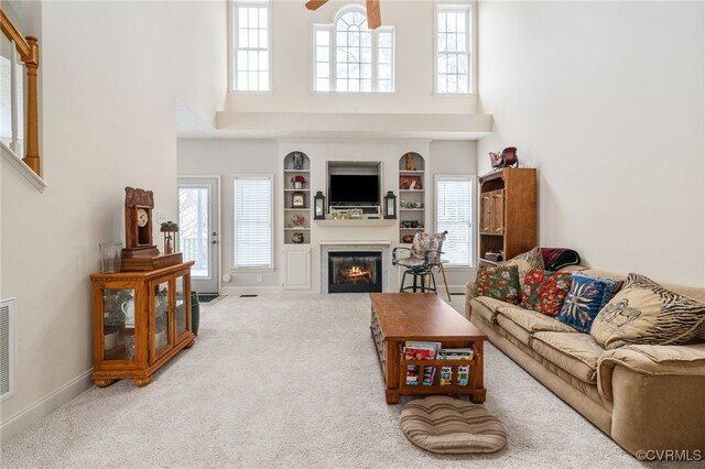 14313 Woodleigh Dr, Chester, VA 23831 - carpeted living area with a high ceiling, a glass covered fireplace, healthy amount of natural light, a ceiling fan, and built in features