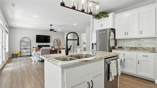 5080 Brandon Pines Way, Providence Forge, VA 23140 - kitchen with appliances with stainless steel finishes, light wood-type flooring, ceiling fan, a center island with sink, and backsplash