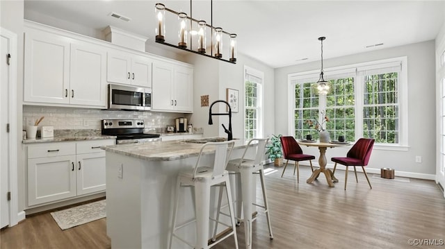 5080 Brandon Pines Way, Providence Forge, VA 23140 - kitchen with appliances with stainless steel finishes, wood finished floors, decorative backsplash, light stone counters, and white cabinets