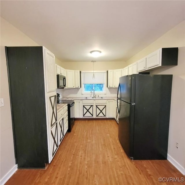 9210 Park St, Amelia Courthouse, VA 23002 - kitchen with black appliances, light wood finished floors, light countertops, white cabinetry, and tasteful backsplash