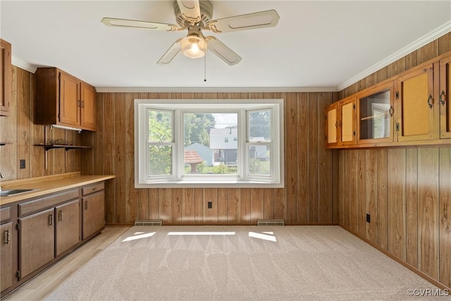 2411 Colwyn Rd, Henrico, VA 23229 - kitchen featuring a ceiling fan, wood walls, ornamental molding, brown cabinetry, and light countertops