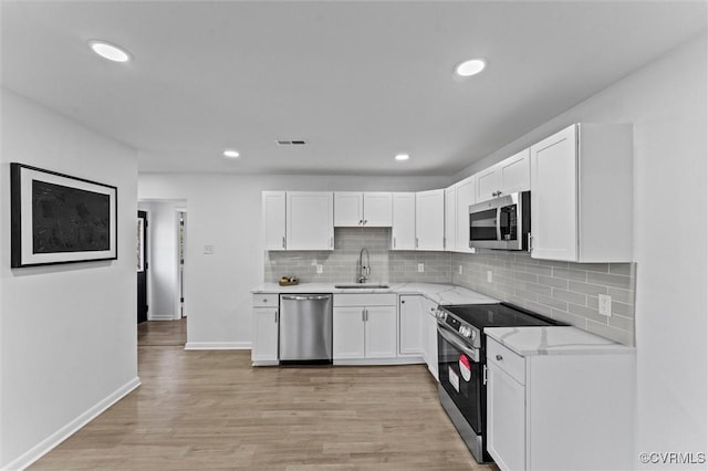 2000 Cleary Rd, Richmond, VA 23223 - kitchen featuring appliances with stainless steel finishes, white cabinets, backsplash, light wood-style flooring, and recessed lighting