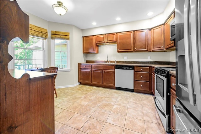 10 Heatherfield Ct Unit 10, Kilmarnock, VA 22482 - kitchen featuring stainless steel appliances, dark countertops, light tile patterned floors, brown cabinetry, and recessed lighting