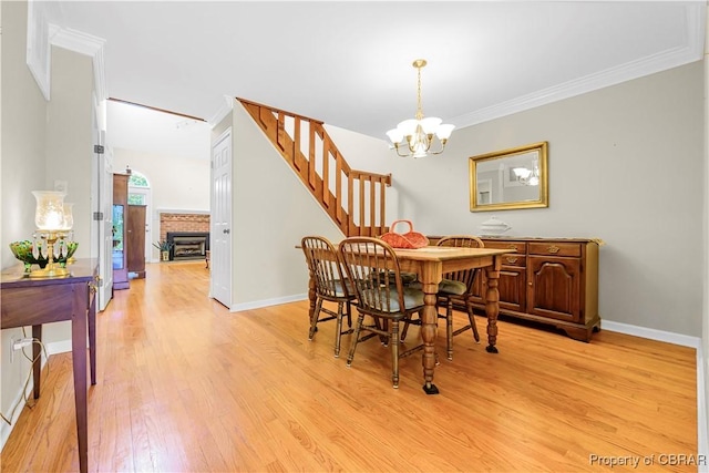 10 Heatherfield Ct Unit 10, Kilmarnock, VA 22482 - dining space with light wood finished floors, a chandelier, stairway, crown molding, and a fireplace