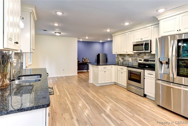 107 Ward, Hampton, VA 23669 - kitchen featuring appliances with stainless steel finishes, a peninsula, tasteful backsplash, white cabinets, and light wood-style flooring