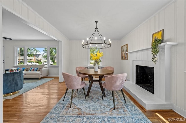 2207 Craven Ln, Henrico, VA 23228 - dining area with wood finished floors, a chandelier, a fireplace with raised hearth, and crown molding