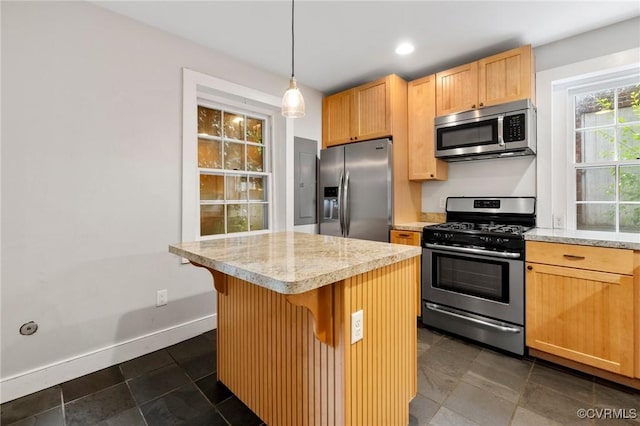 2502 E Grace St, Richmond, VA 23223 - kitchen featuring stainless steel appliances, light brown cabinetry, a kitchen island, a breakfast bar area, and pendant lighting