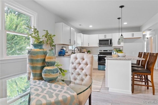 606 Bermuda Hundred Rd, Chester, VA 23836 - kitchen featuring appliances with stainless steel finishes, backsplash, light wood finished floors, white cabinetry, and hanging light fixtures