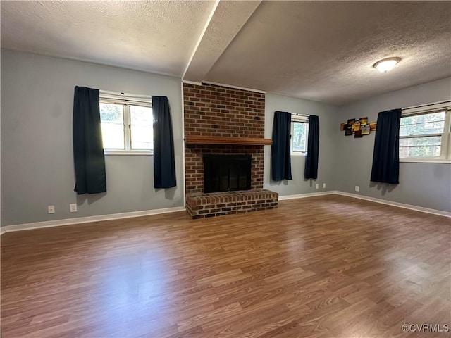 8253 Skirmish Ln, Mechanicsville, VA 23111 - unfurnished living room with a textured ceiling, wood finished floors, healthy amount of natural light, and a brick fireplace