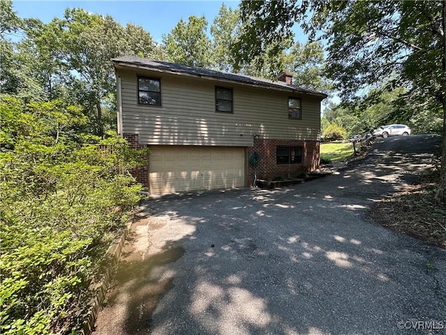8253 Skirmish Ln, Mechanicsville, VA 23111 - view of property exterior with brick siding, driveway, a chimney, and a garage