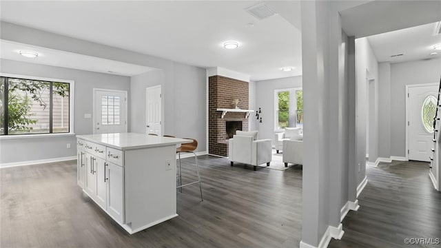1531 Berkeley Ave, Petersburg, VA 23805 - kitchen featuring dark wood-style floors, white cabinets, a kitchen bar, and healthy amount of natural light
