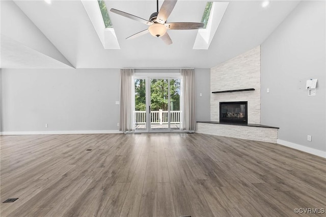 3130 Tinsley Ter, Prince George, VA 23875 - unfurnished living room featuring a skylight, high vaulted ceiling, ceiling fan, wood finished floors, and a stone fireplace