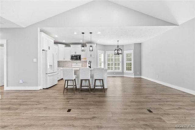 3130 Tinsley Ter, Prince George, VA 23875 - kitchen featuring stainless steel microwave, white refrigerator with ice dispenser, lofted ceiling, white cabinets, and light wood finished floors