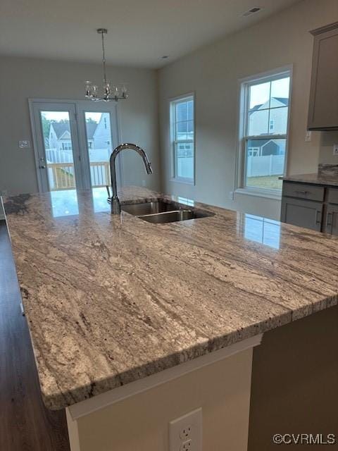7079 Hepworth Dr, Henrico, VA 23231 - kitchen with a large island, light stone countertops, wood finished floors, a chandelier, and hanging light fixtures