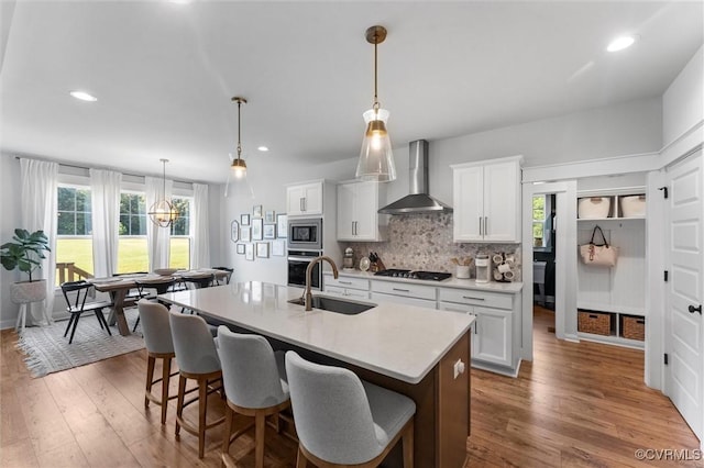 3616 Bonnies Way, Powhatan, VA 23139 - kitchen with wall chimney exhaust hood, stainless steel appliances, an island with sink, light countertops, and healthy amount of natural light